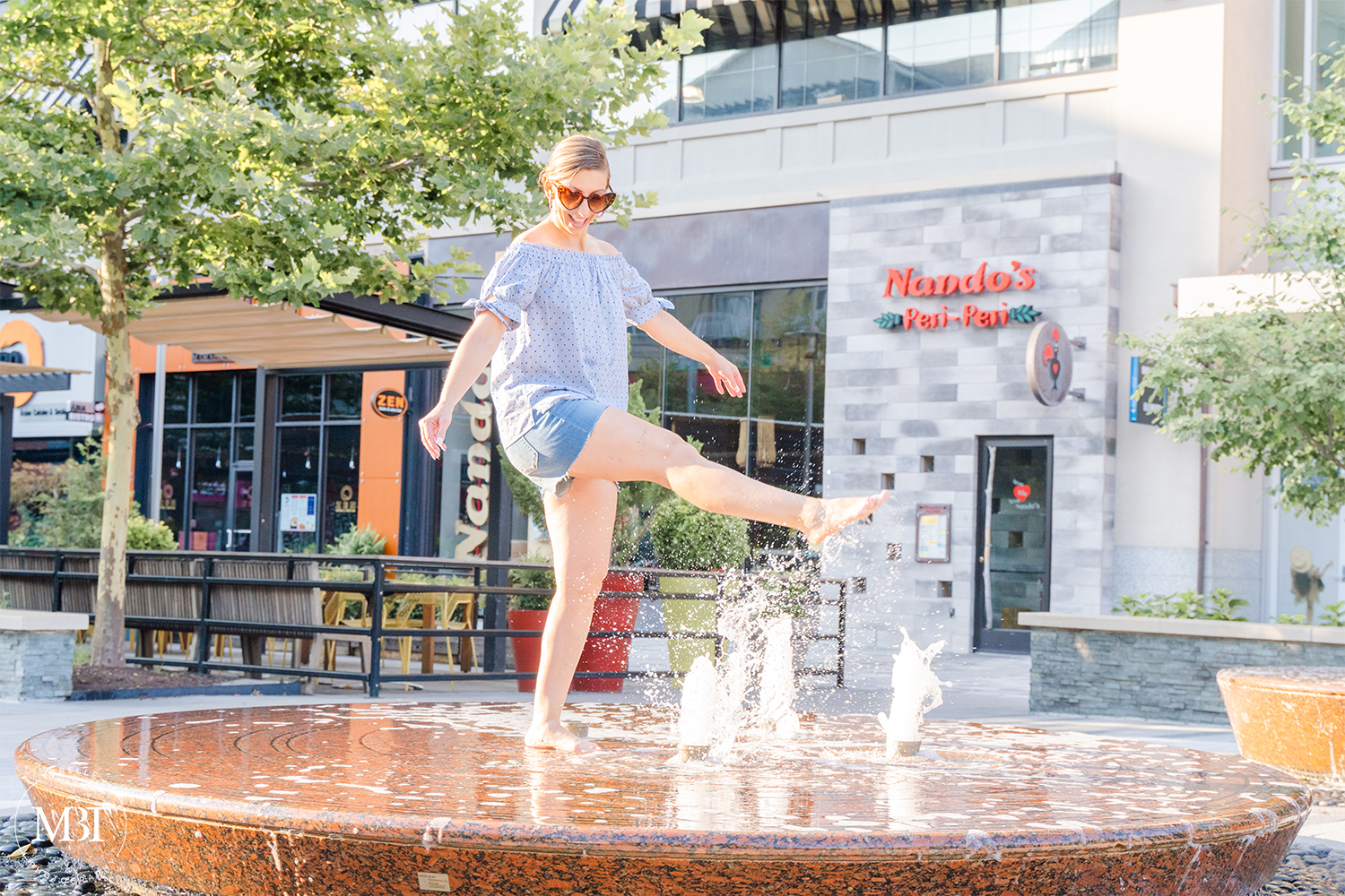 woman wearing off the shoulder top, denim shots playing in the fountain, lifestyle session taken in Arlington, Virginia by a personal branding photographer in Washington, DC