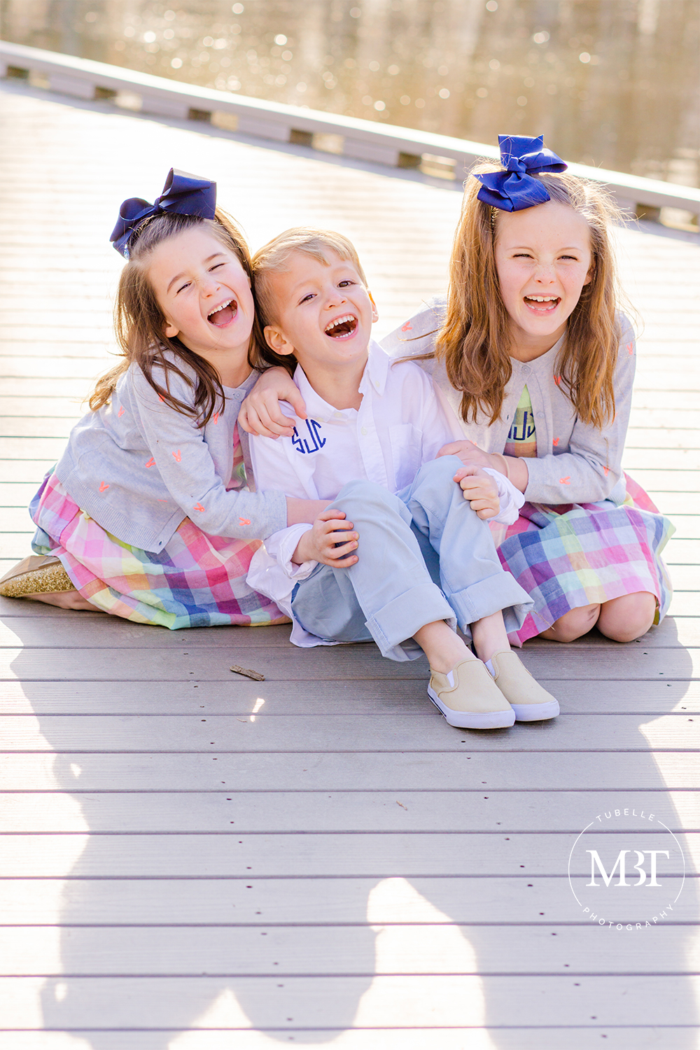 siblings, girls and boy, dressed in coordinating outfits sitting on a bridge and laughing, taken in Alexandria, Virginia by a children's photographer in Northern Virginia