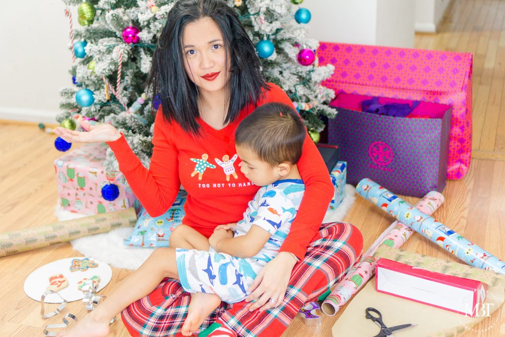 Mommy holding son surrounded by wrapping paper, gifts, cookies, and Christmas tree on Christmas